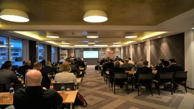 Eine Gruppe von Teilnehmenden des Branchenevents am Vorabend der Heilbronner Aufzugstage sitzt auf Stühlen und schaut auf die Bühne. 