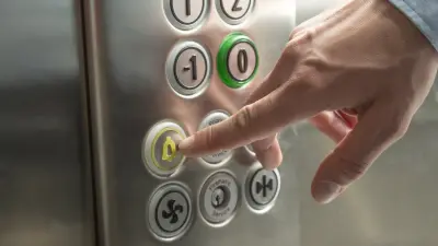 Ein Hand drückt auf den Notrufknopf im Aufzug.