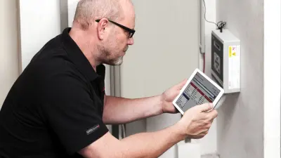 Detlef se agacha sobre un instrumento de medición. Mira una tableta.