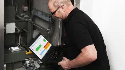 Detlef se agacha cerca de un hueco de ascensor. Mira al portátil apoyado en su regazo.