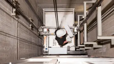 Ein Aufzugtechniker inspiziert einen Aufzugschacht.